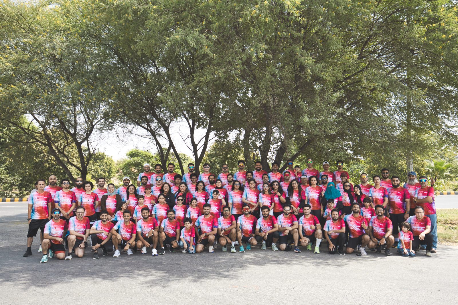 Falcon Triathlon Club members in pink and blue club jerseys under a tree canopy
