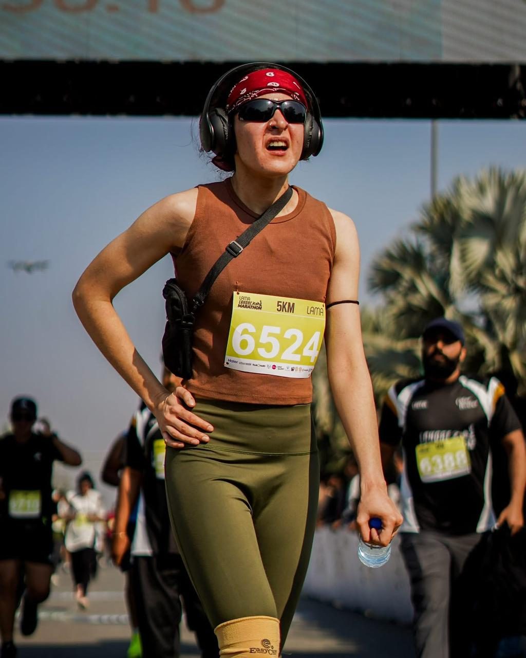 A woman in a red bandana and headphones running the 5K